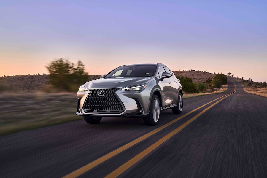 A gray 2025 Lexus NX SUV driving down a road at sunset