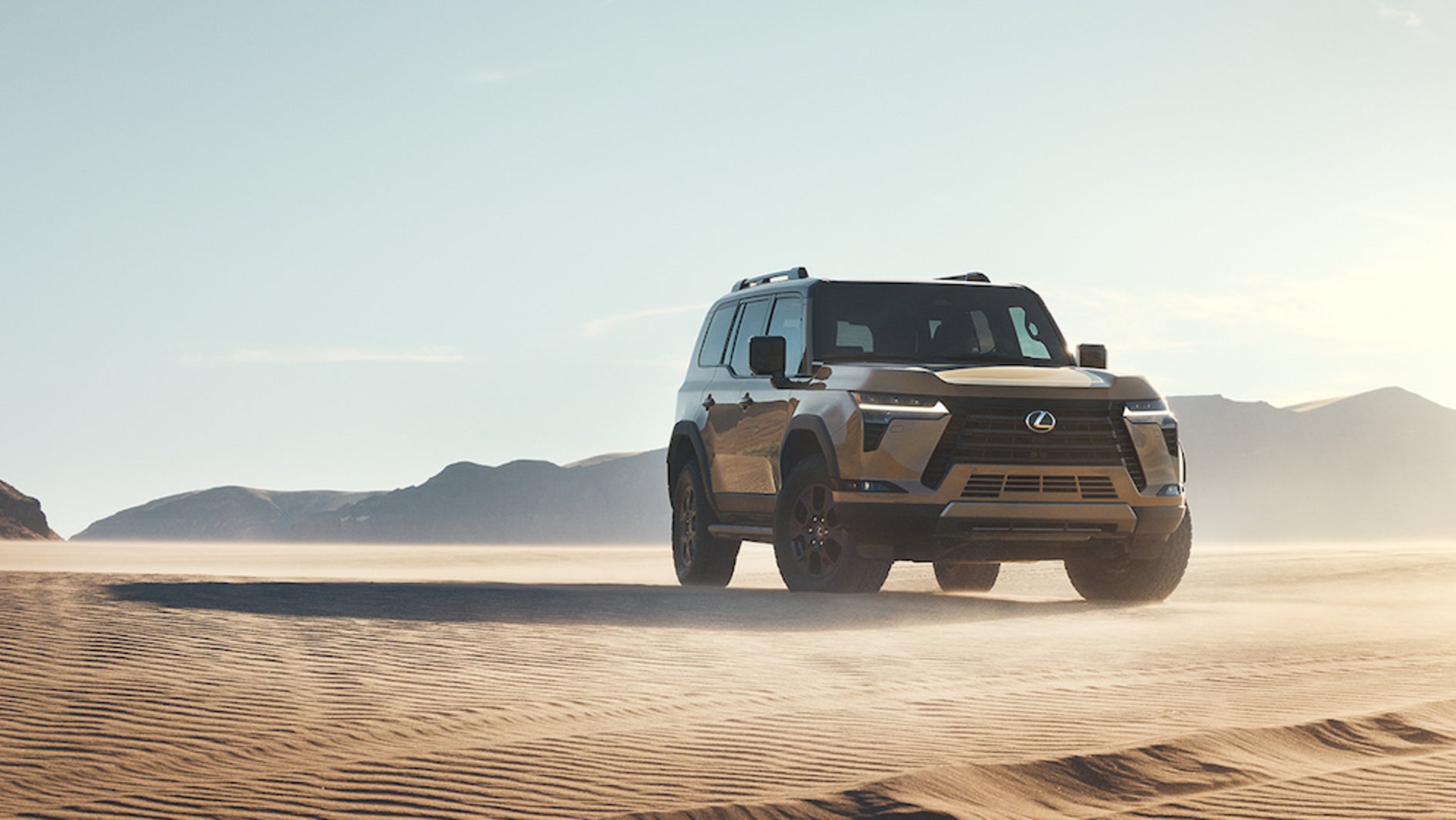 A light-colored 2026 Lexus GX SUV driving over sand dunes