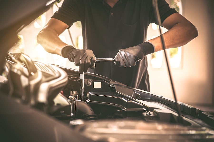 A mechanic wearing gloves working on a vehicle’s engine