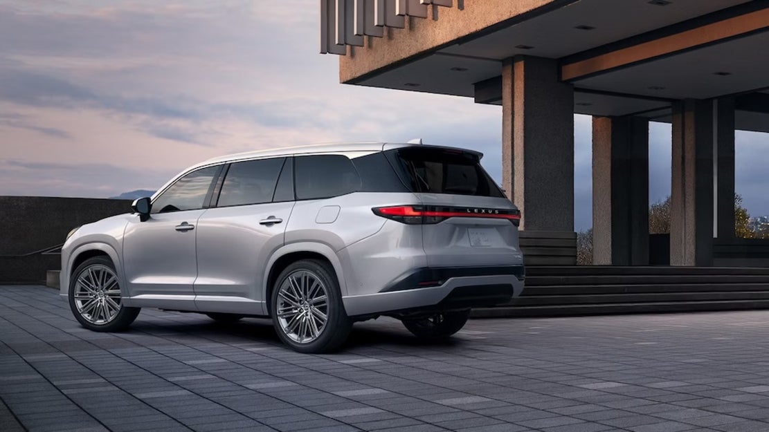 A silver 2026 Lexus TX SUV parked on a patio overlooking the sunset