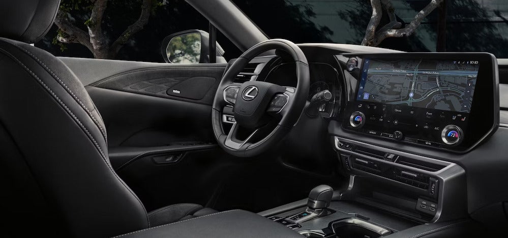 The front seat, steering wheel and dashboard of a 2026 Lexus RX SUV, featuring black upholstery and a large navigation display