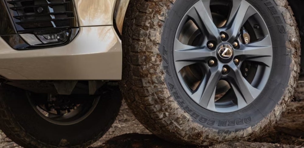 A close-up of a mud-spattered tire of a beige 2026 Lexus LX