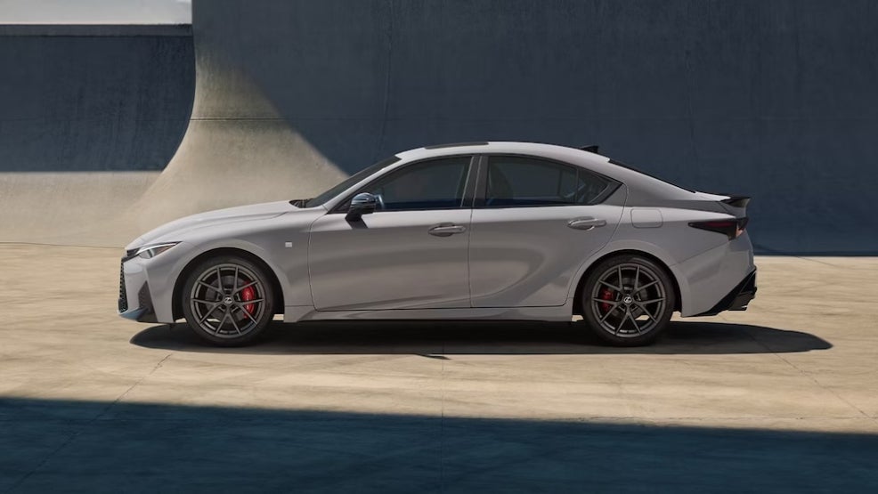 A gray Lexus IS sedan parked near a concrete wall